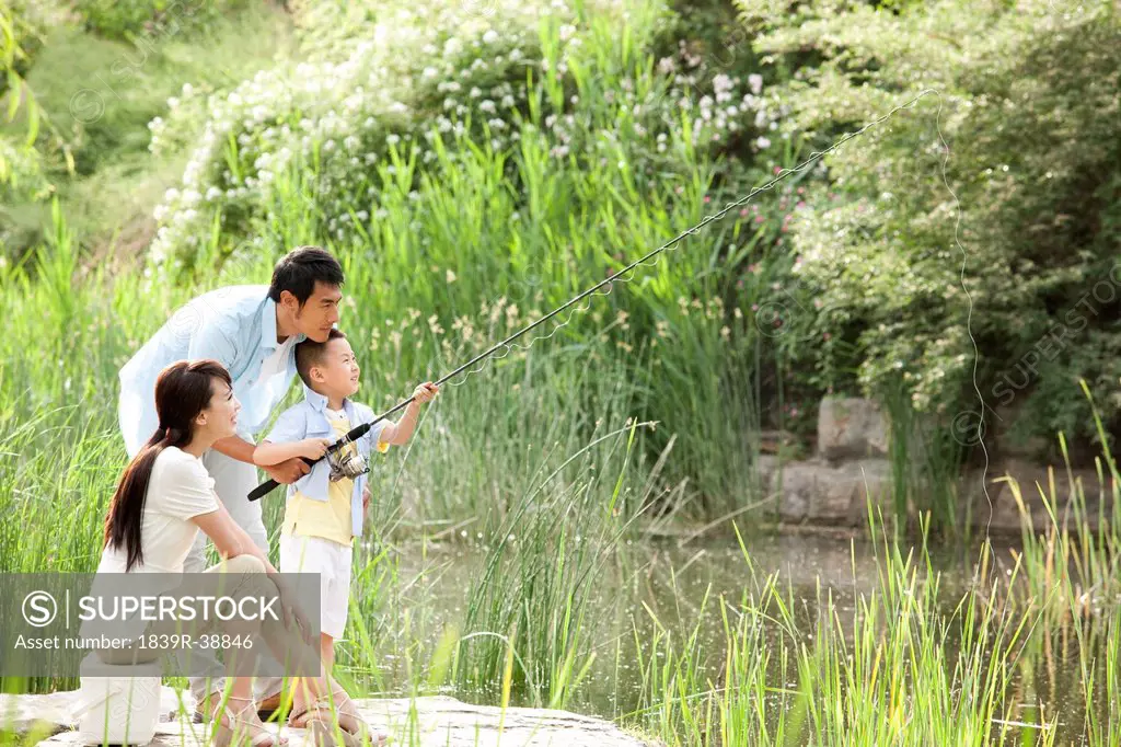 Cheerful Chinese family fishing in a park