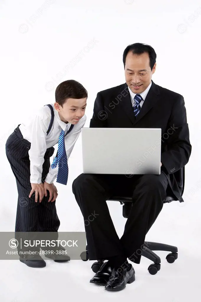 Father Showing His Son A Laptop And Smiling