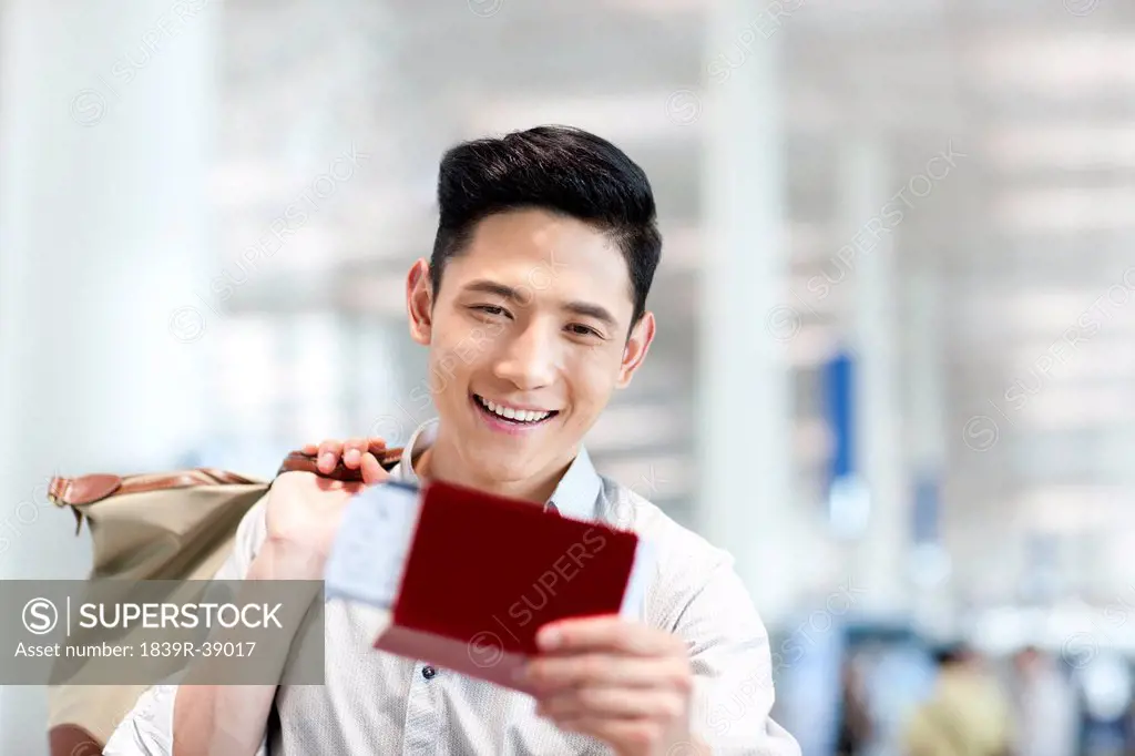 Excited young man at the airport with flight ticket and passport