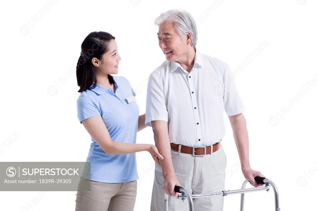 Female nursing assistant helping senior man with walking frame