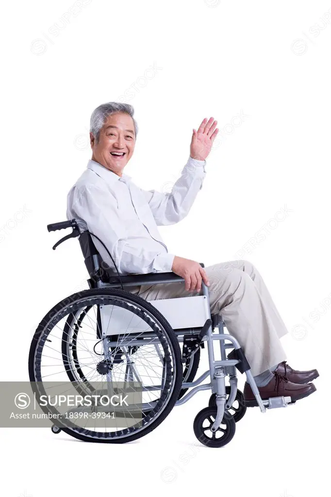 Smiling senior man in wheelchair waving