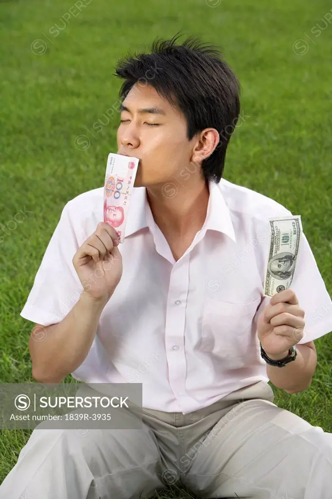 Man Sitting In A Park Kissing Money
