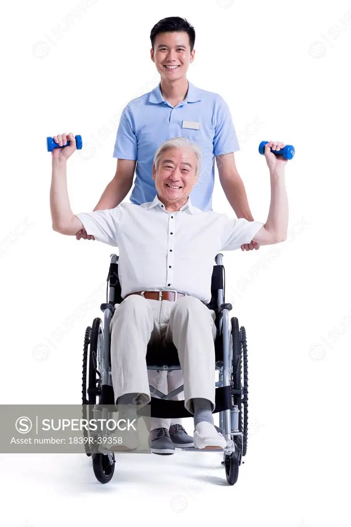 Male nursing worker helping senior man doing exercise