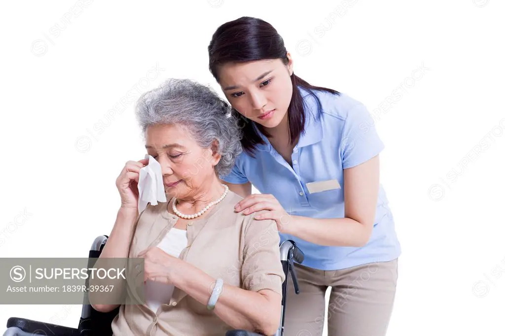 Female nursing worker comforting weeping senior woman