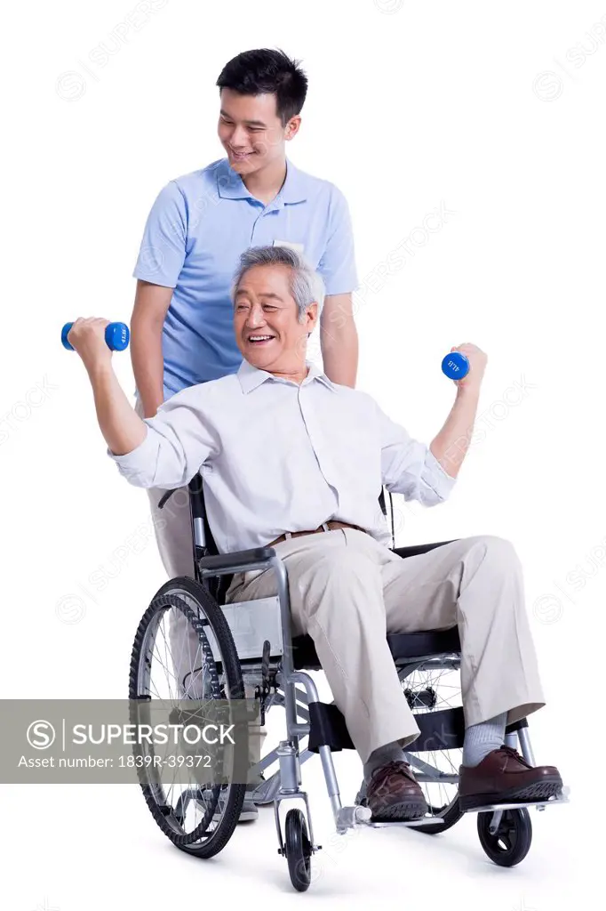 Male nursing worker helping senior man doing exercise