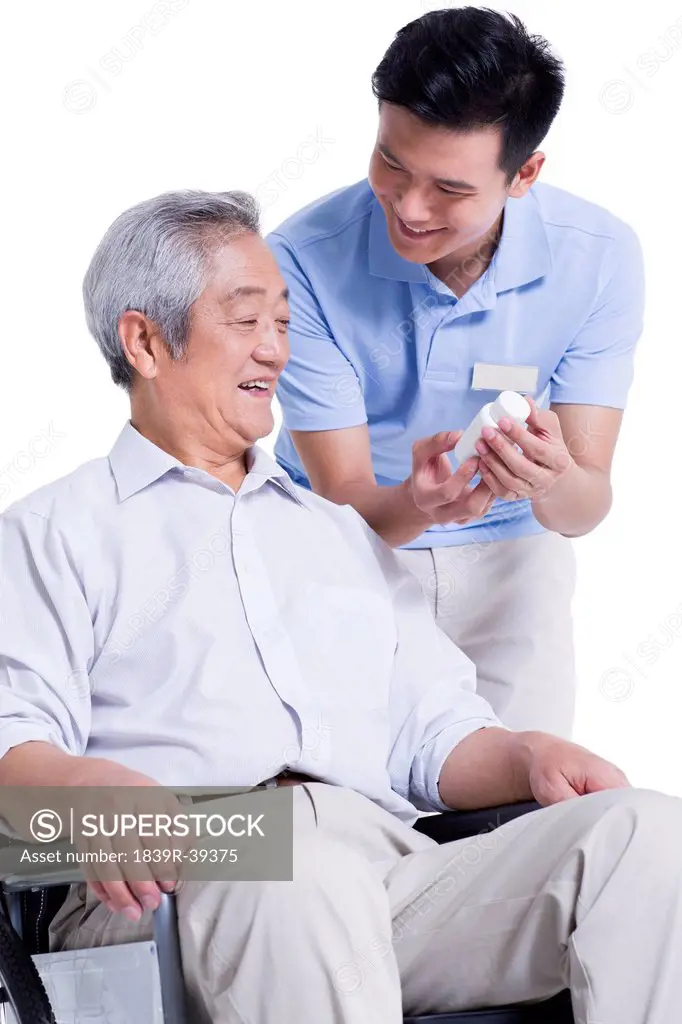 Male nursing worker showing senior man medicine