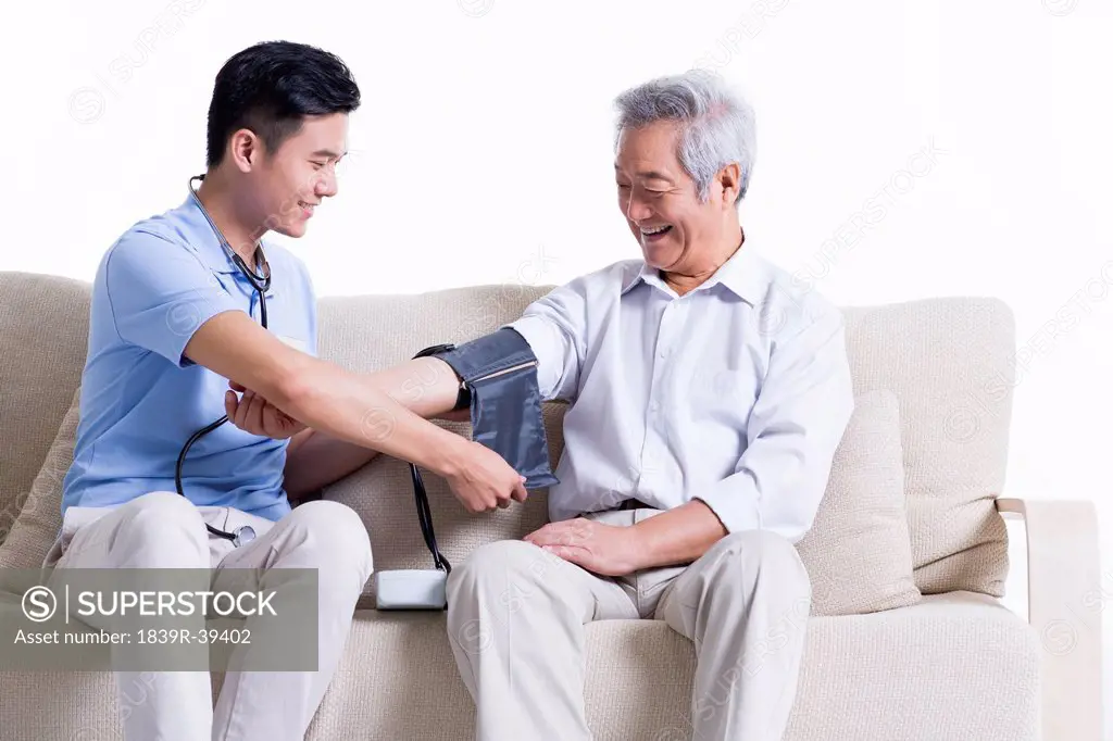 Nursing assistant taking senior man's blood pressure