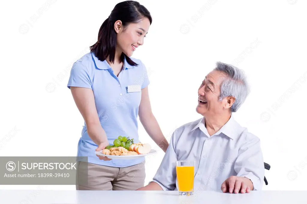 Nursing assistant serving food for disabled senior man
