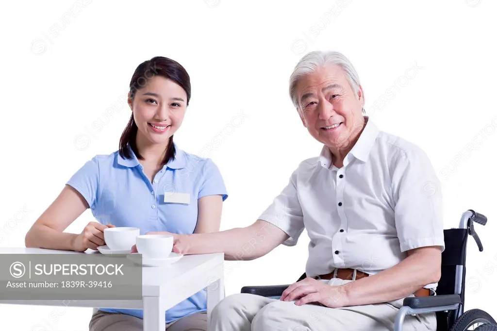 Disabled senior man having a coffee break with nursing assistant