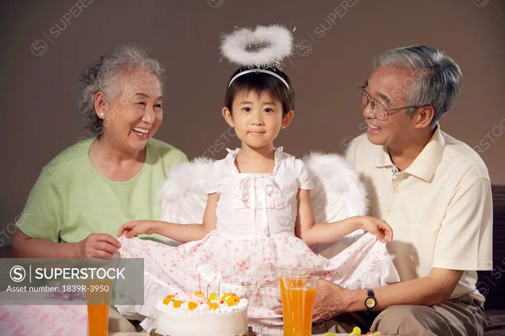 Grandparents Smiling At Their Granddaughter Who Is Dressed Up As An Angel