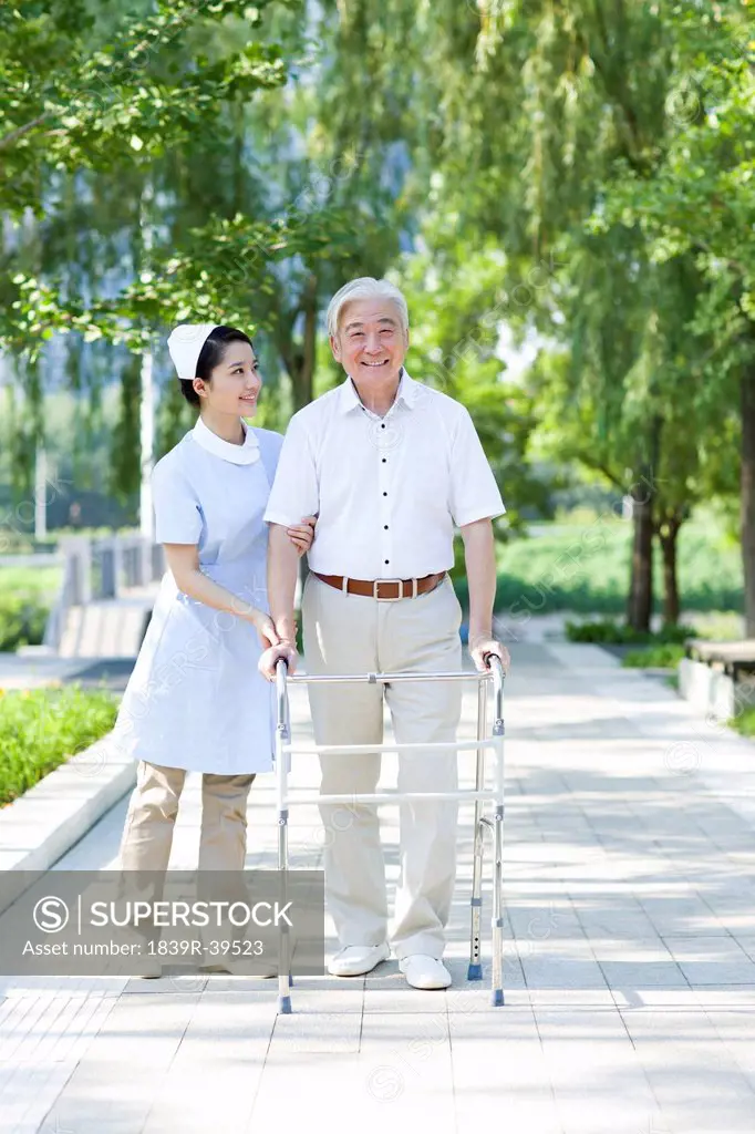 Senior man with walking frame under nurse's assistance