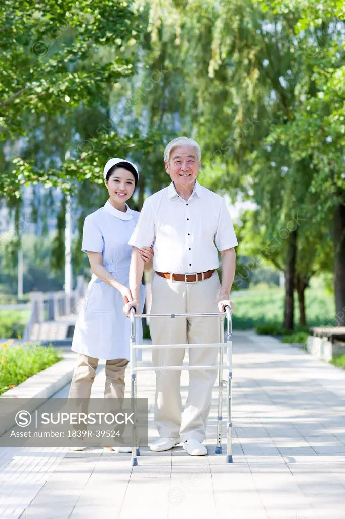 Senior man walking with walking frame under nurse's assistance