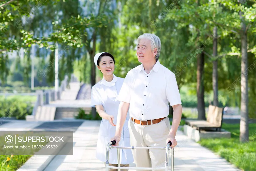 Senior man walking with walking frame under nurse's assistance