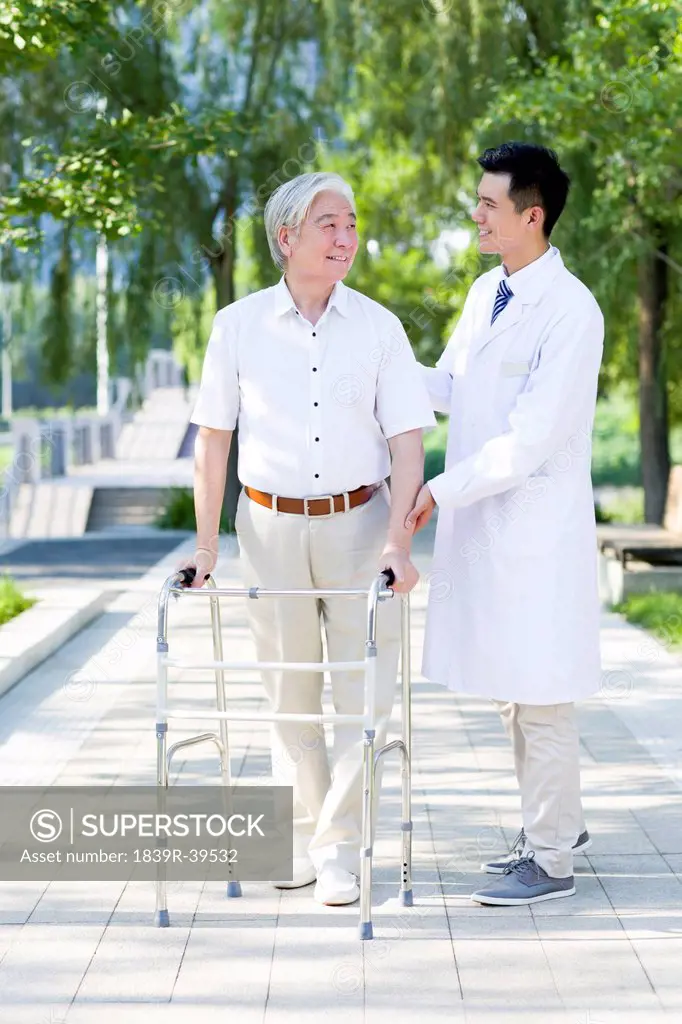 Senior man walking with walking frame under doctor's assistance
