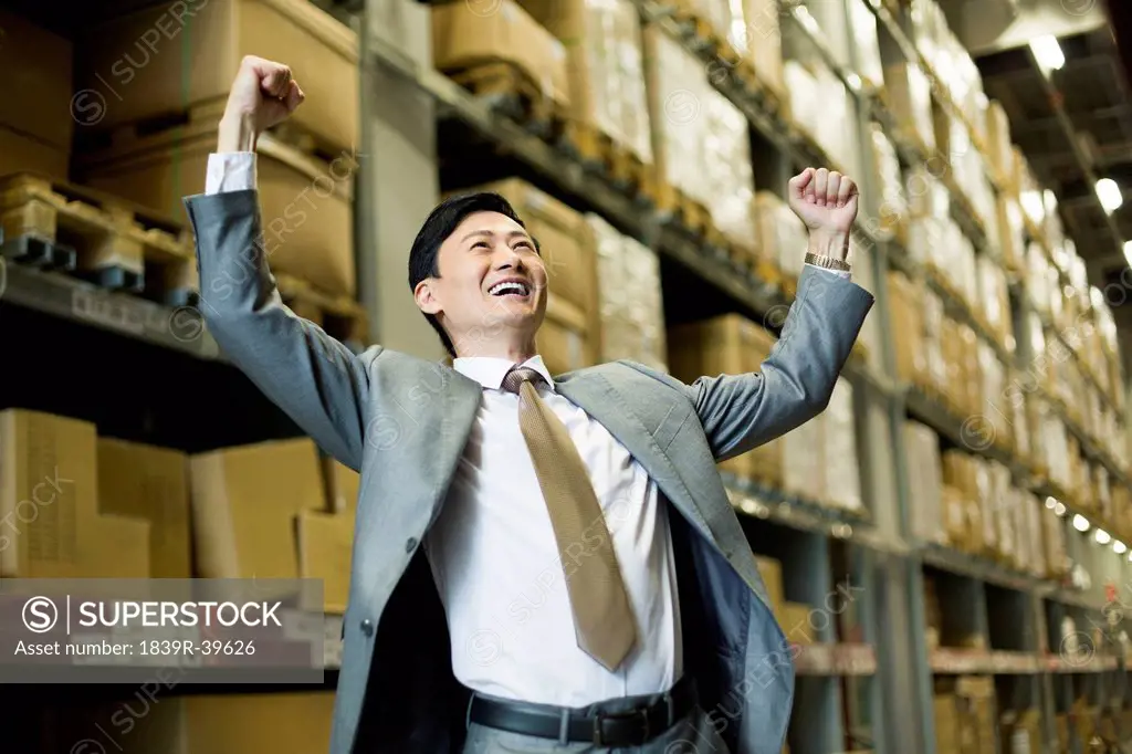 Cheerful businessman punching the air in warehouse