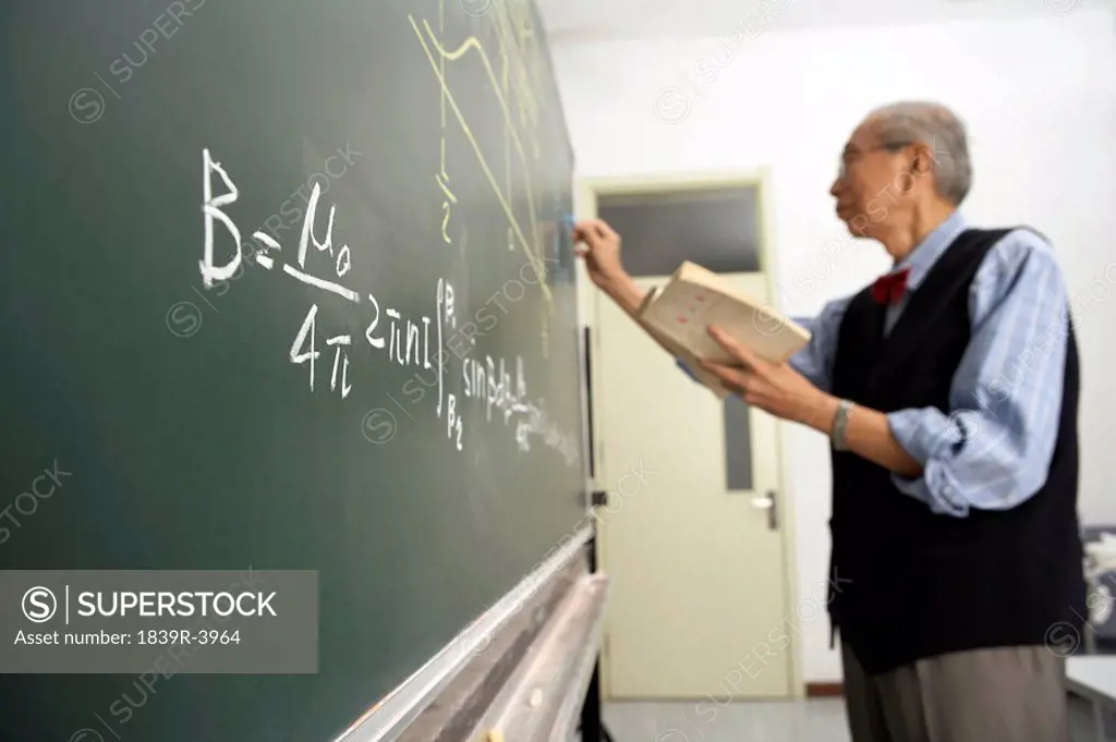 Teacher Writing On Blackboard