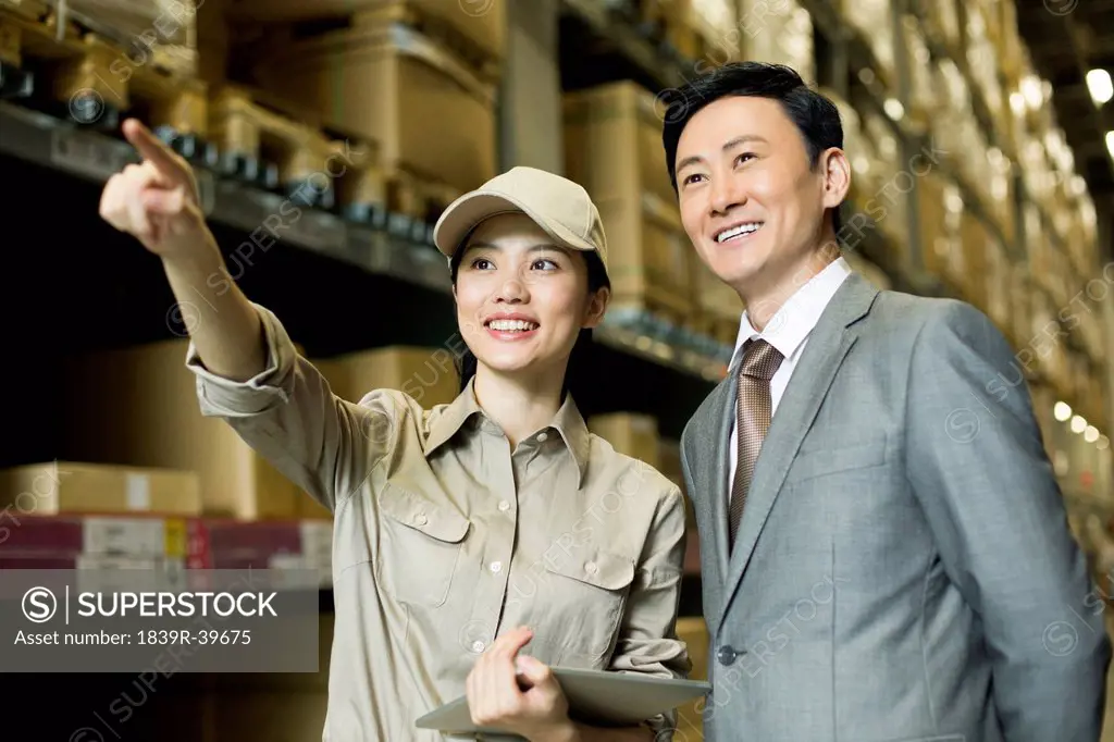 Female logistics staff with businessman in warehouse