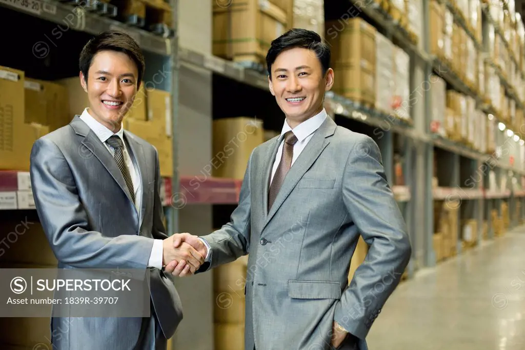 Business partners shaking hands in logistic warehouse