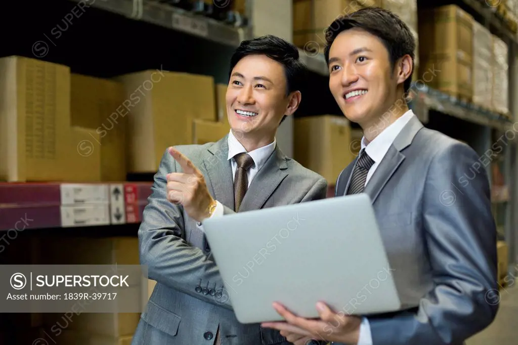 Business partners with laptop in logistic warehouse