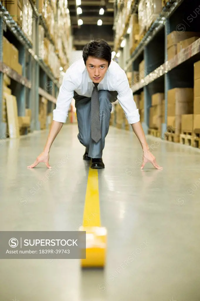Confident businessman ready to run in warehouse