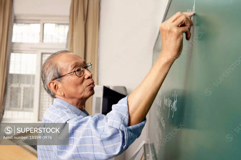 Teacher Writing On Blackboard