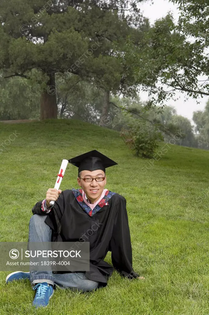Portrait Of Young Man In The Park With Graduation Scroll