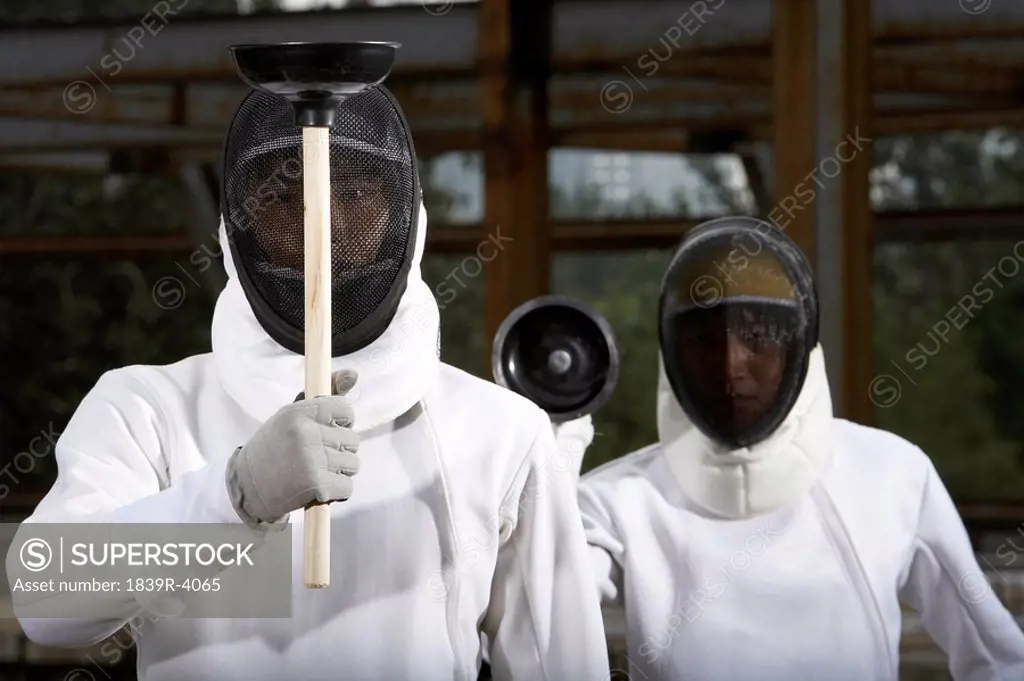 Men In Fencing Suits With Plungers In A Construction Site