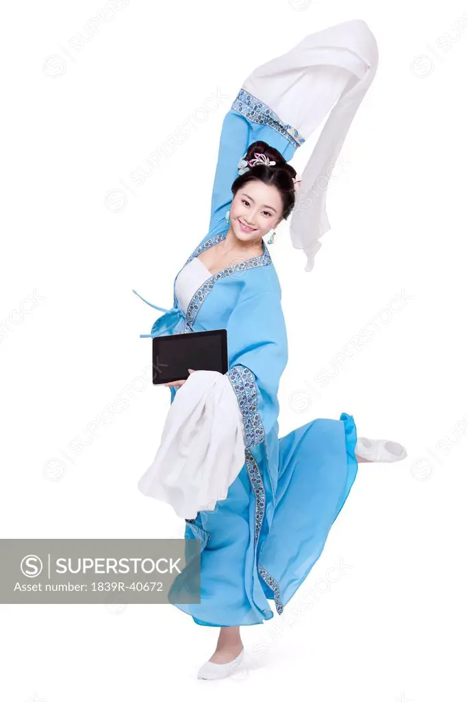 Young woman in traditional Chinese costume dancing with digital tablet in hand