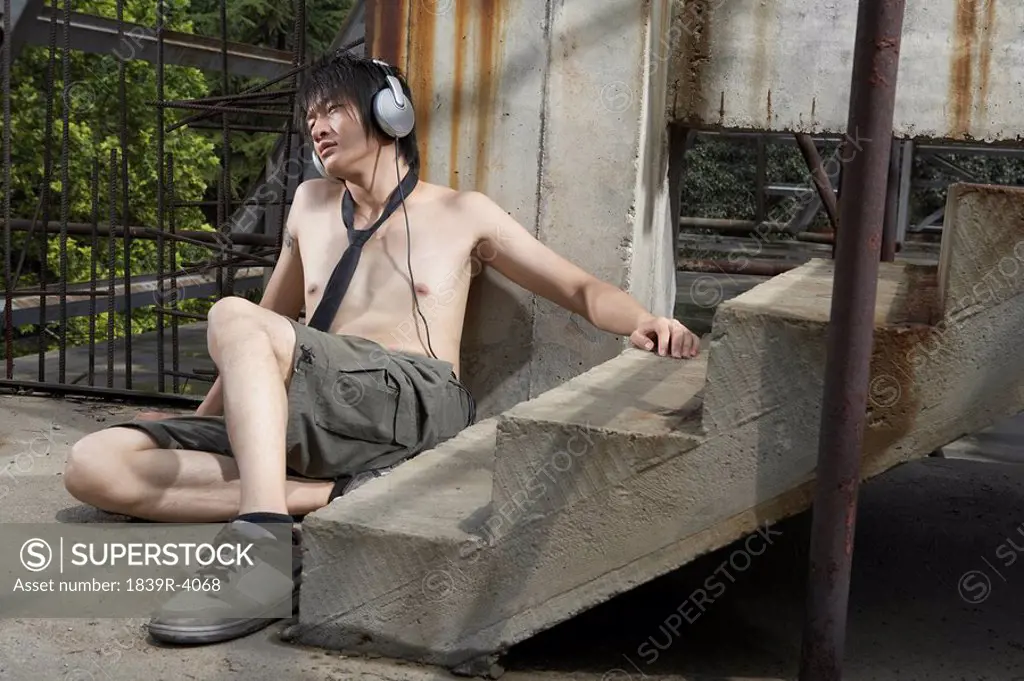 Shirtless Young Man Wearing Headphones In Construction Site