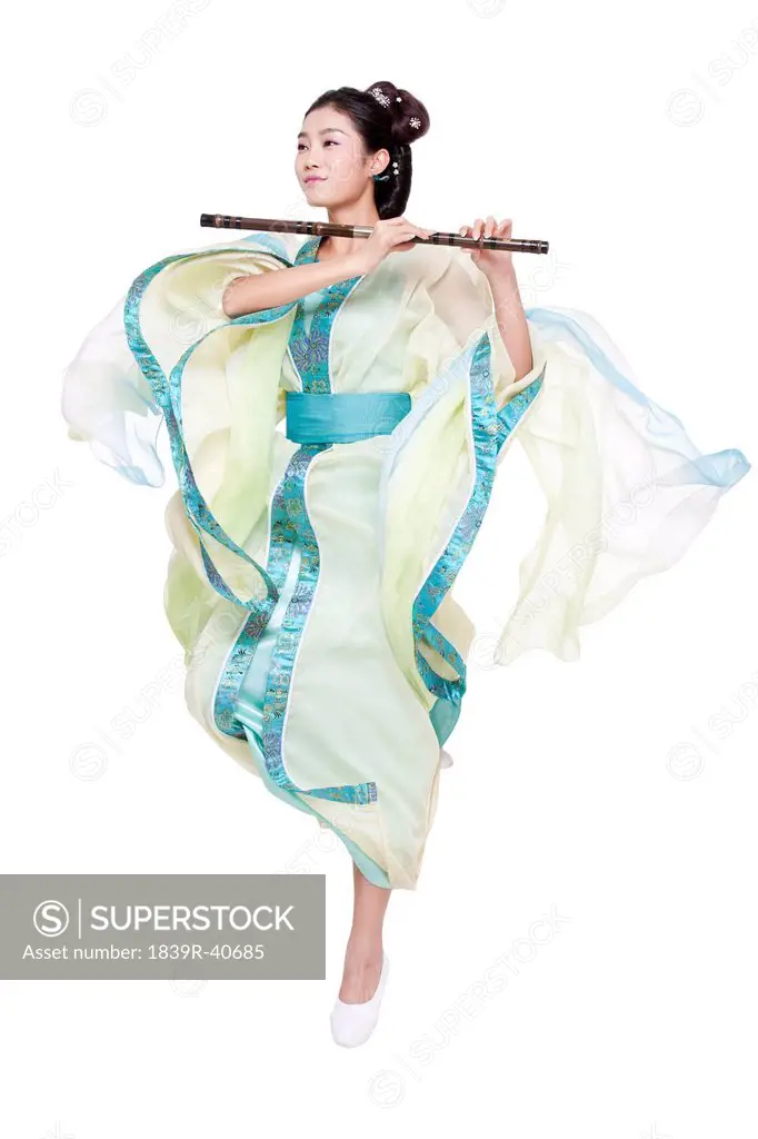 Young woman in Chinese traditional costume blowing Chinese flute