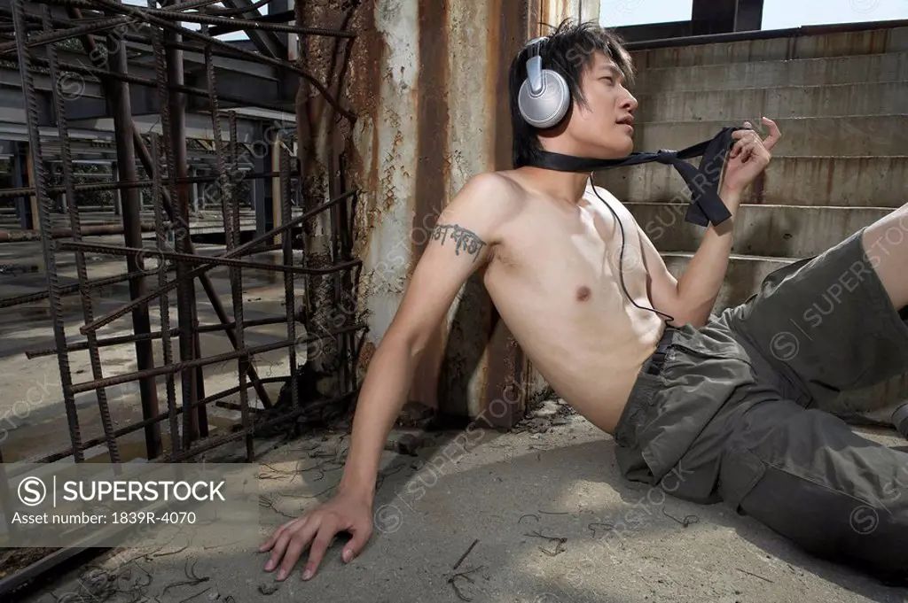 Shirtless Young Man Wearing Headphones In Construction Site