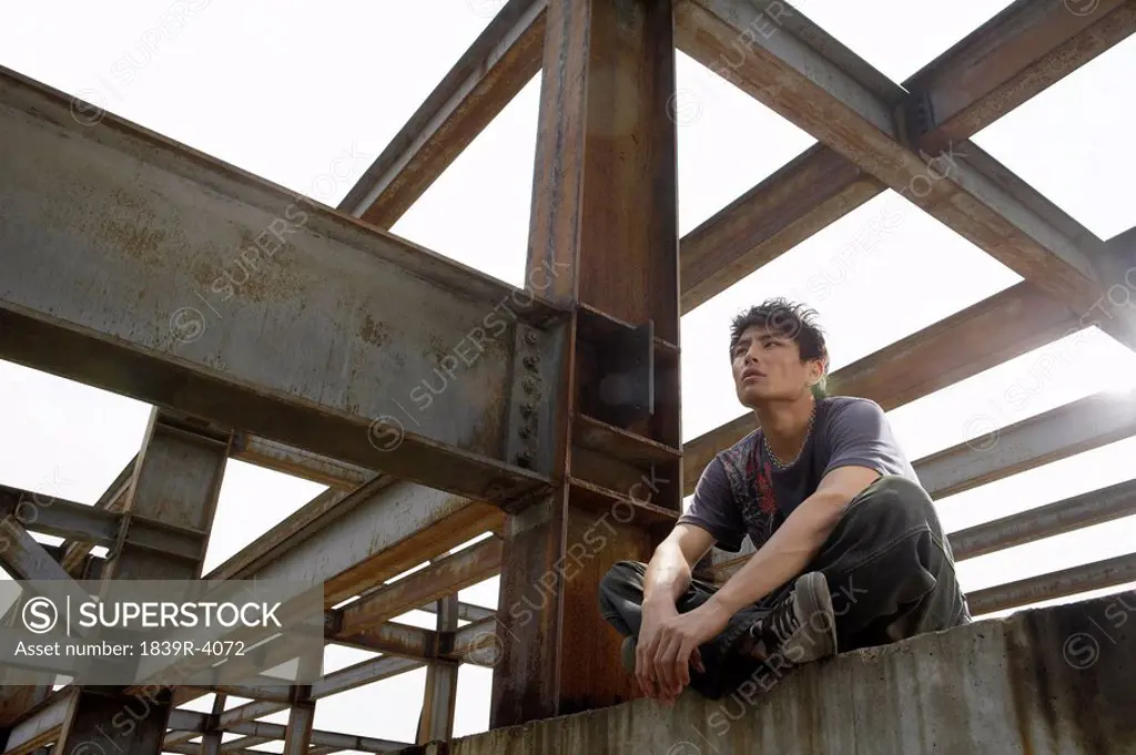 Young Man Sitting On A Beam In A Construction Site