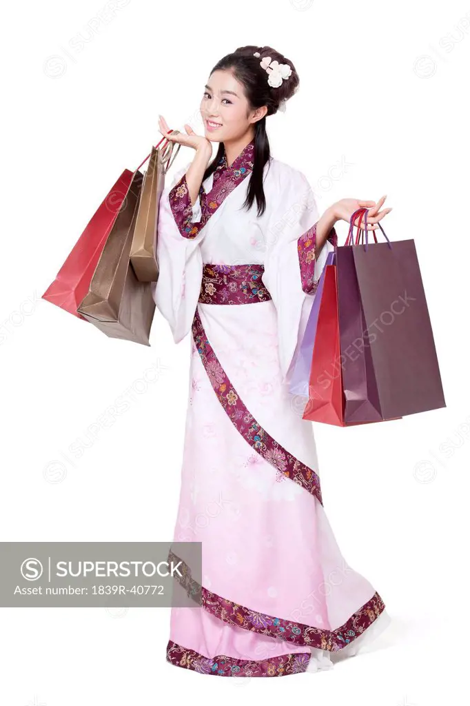Happy young woman in traditional Chinese costume with shopping bags