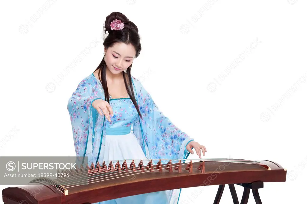 Young woman in Chinese traditional costume plucking Chinese zither