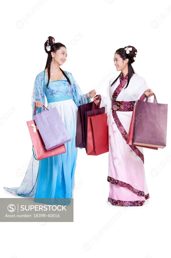 Cheerful young women in traditional Chinese costume with shopping bags face to face