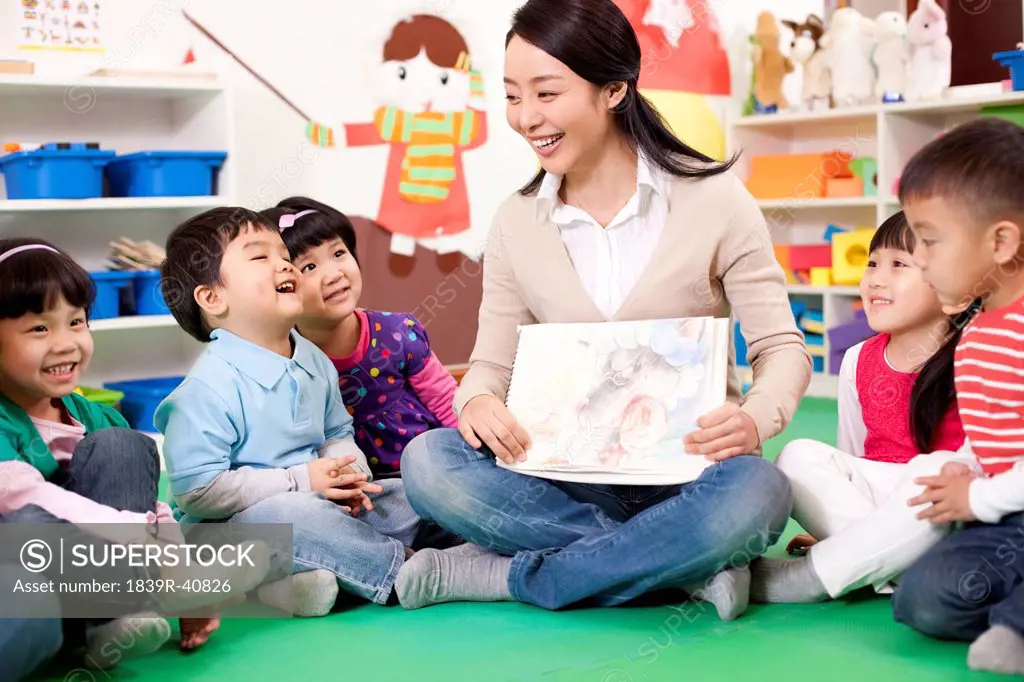 Female teacher showing kindergarten children picture book