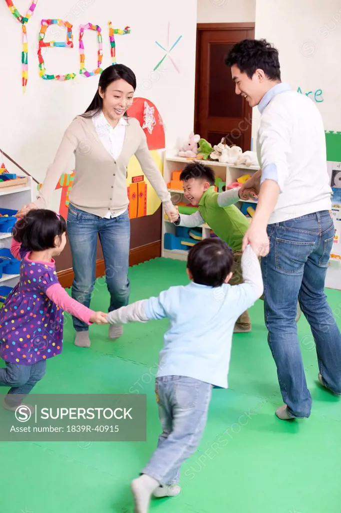 Cheerful kindergarten children playing games with teachers