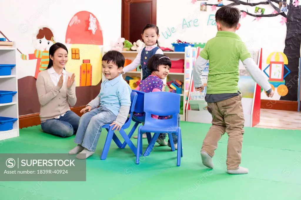 Happy kindergarten children playing musical chairs
