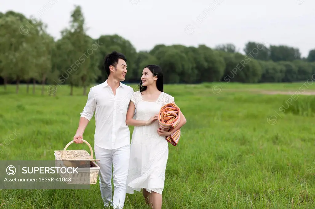 Happy young couple going for a picnic on the grass