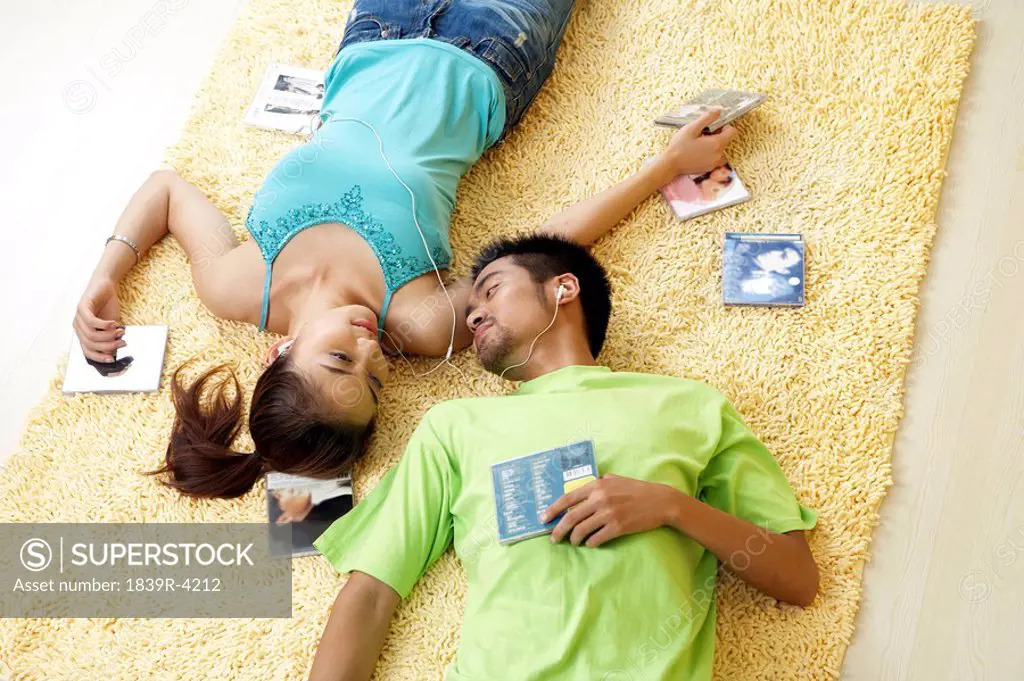 Young Couple Laying On The Floor, Smiling At Each Other