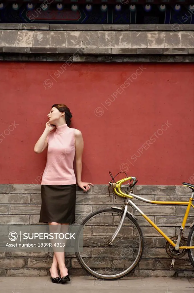 Young Woman Leaning On Wall Talking On Cellphone