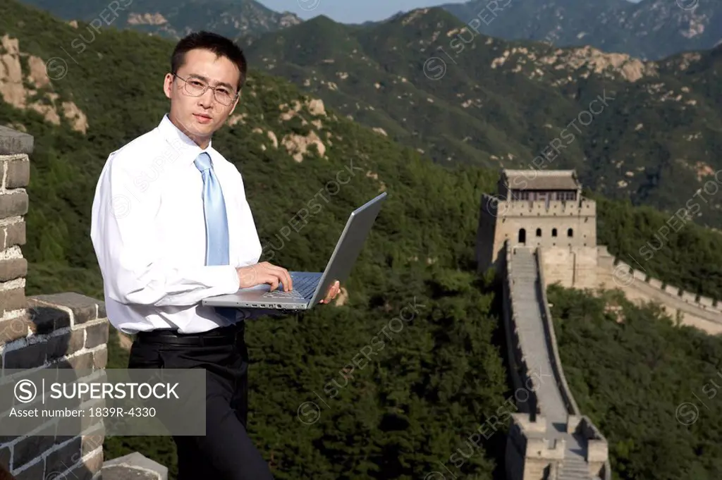 Businessman Typing On Laptop Computer On The Great Wall Of China