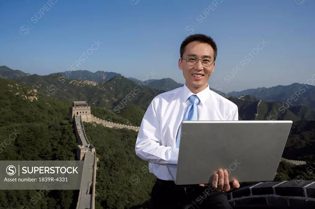Businessman Typing On Laptop Computer On The Great Wall Of China