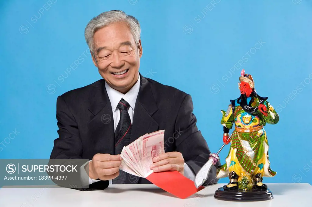 Businessman Sitting At Table With Traditional Objects
