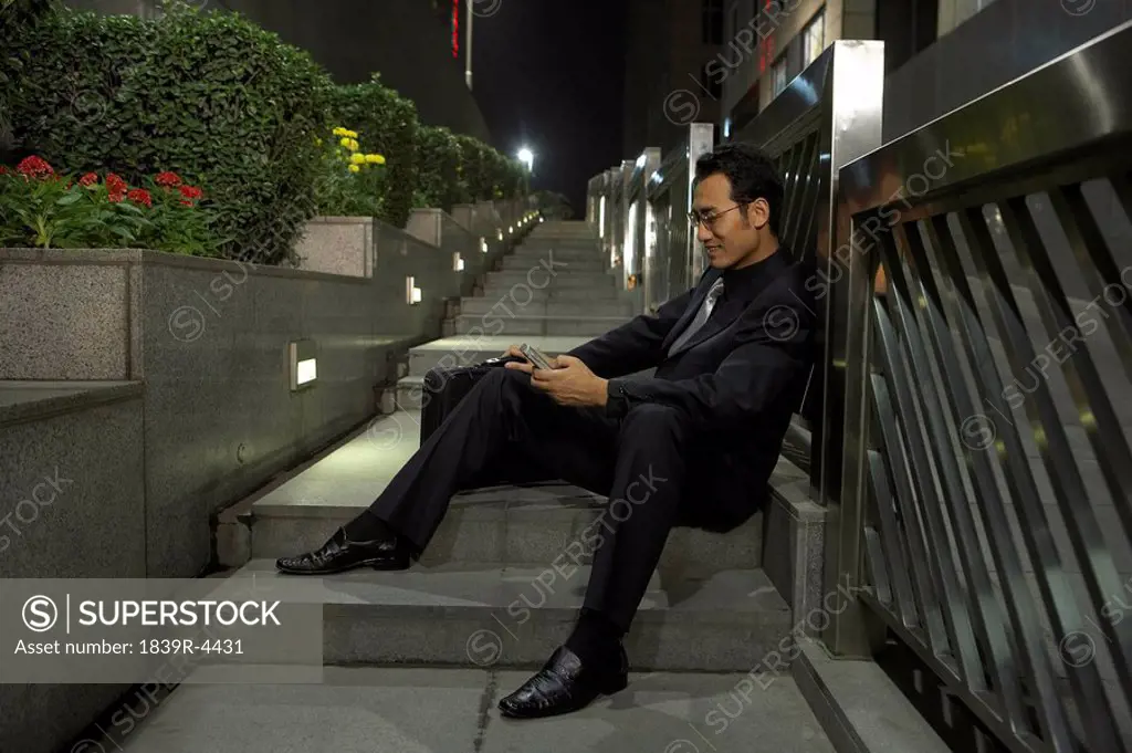Businessman Using Cellphone While Sitting On Steps