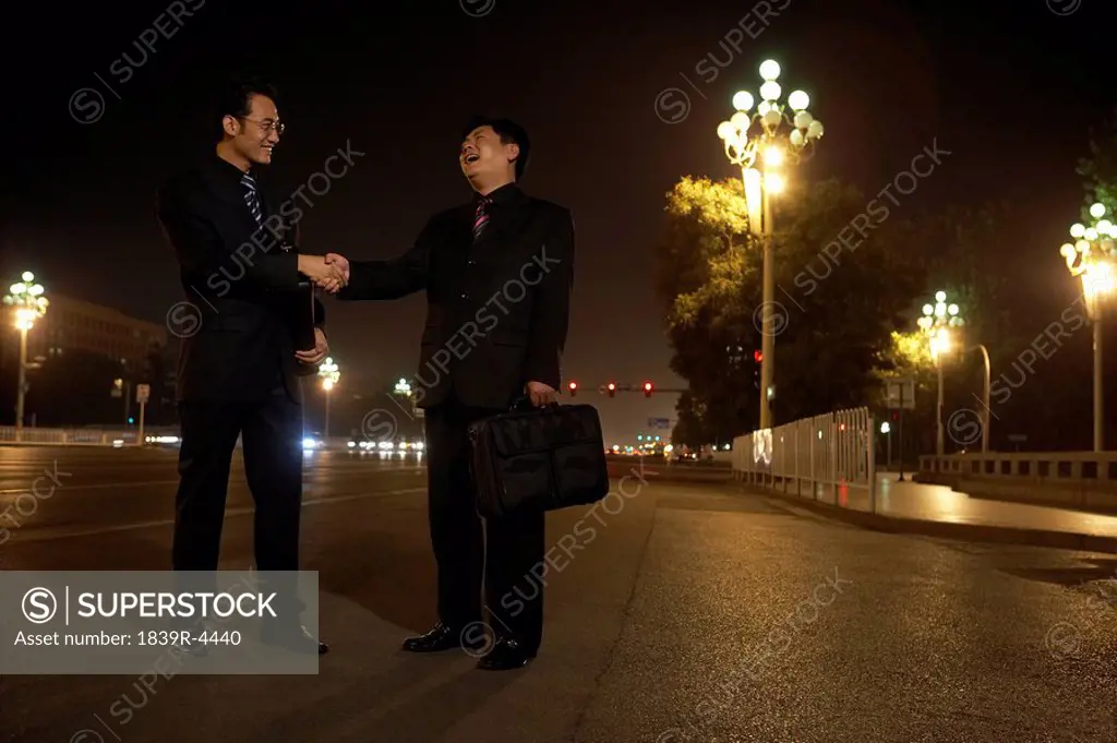 Two Businessmen Shaking Hands Outside At Night