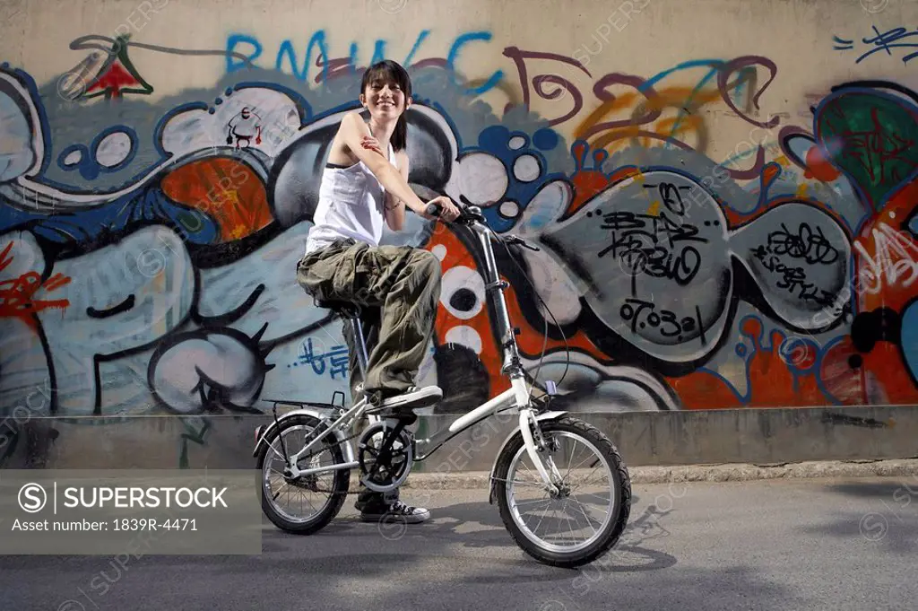 Teenage Girl On Bike In Front Of A Wall Of Graffiti