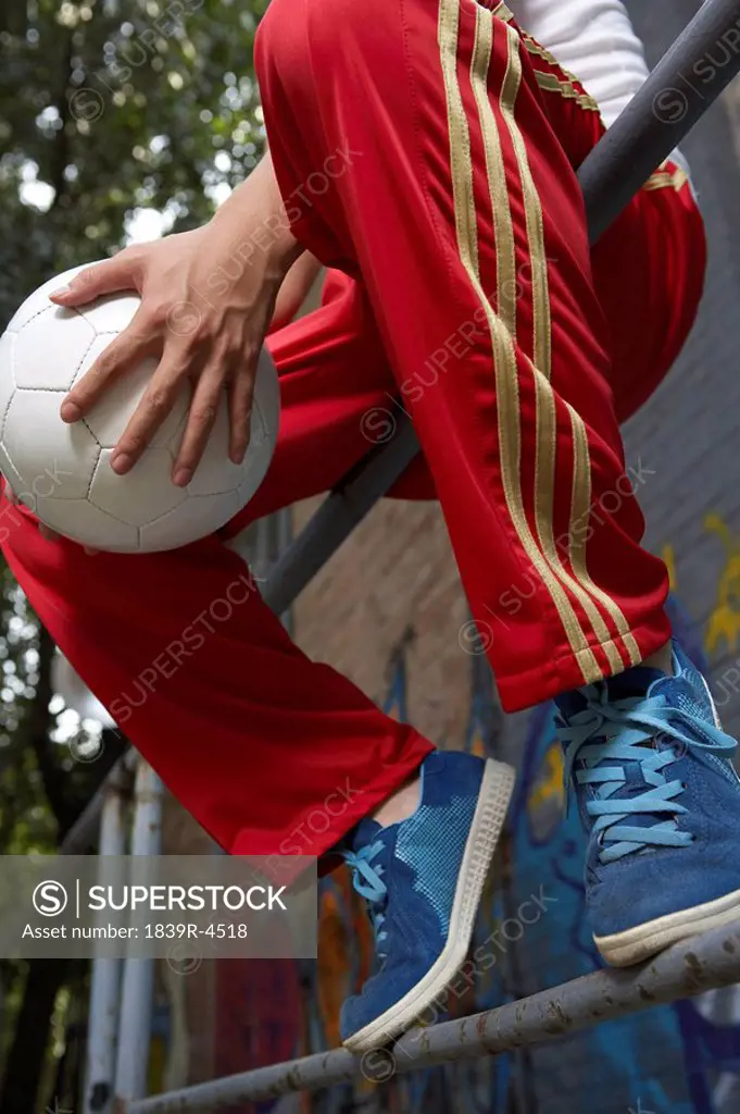 Low Section Shot Of Boy In Casual Clothes Holding Ball