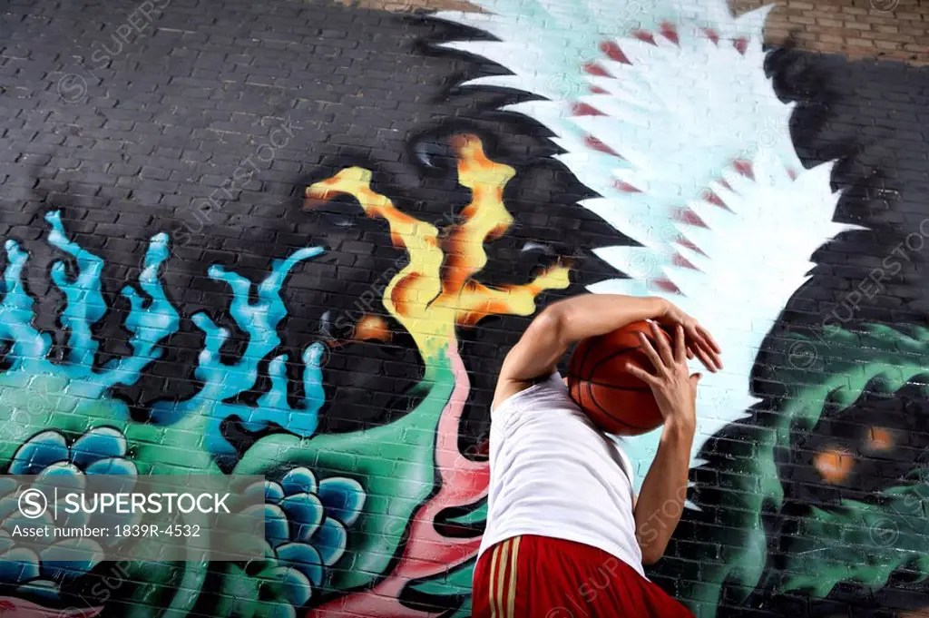 Teenage Boy With Obscured Face Standing Next To Spray Painted Mural