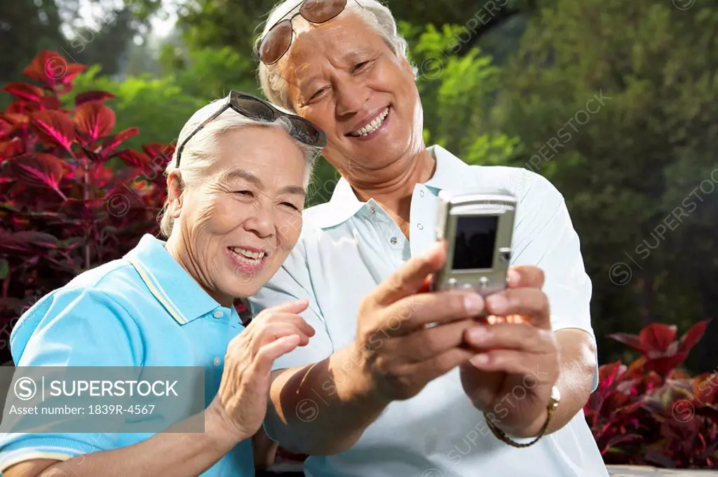 Older Couple Taking Digital Photograph Of Themselves